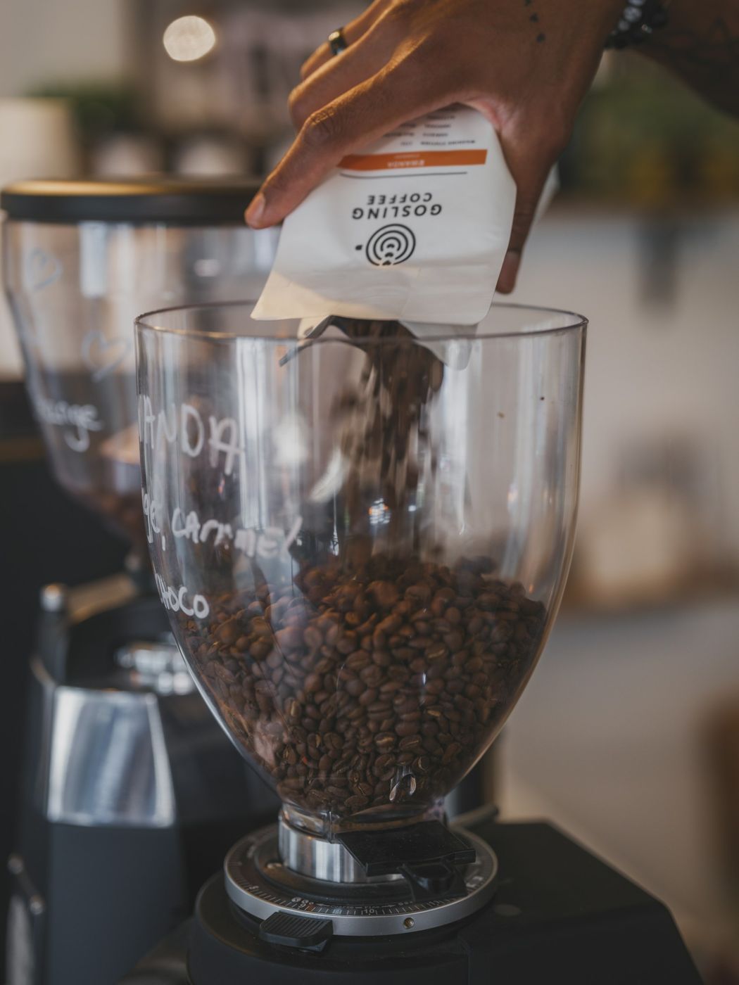 Whole beans being poured into a burr grinder hopper