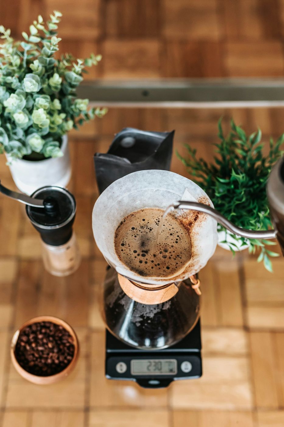 Top-down view of a dripper brewing over a scale on a wooden bar