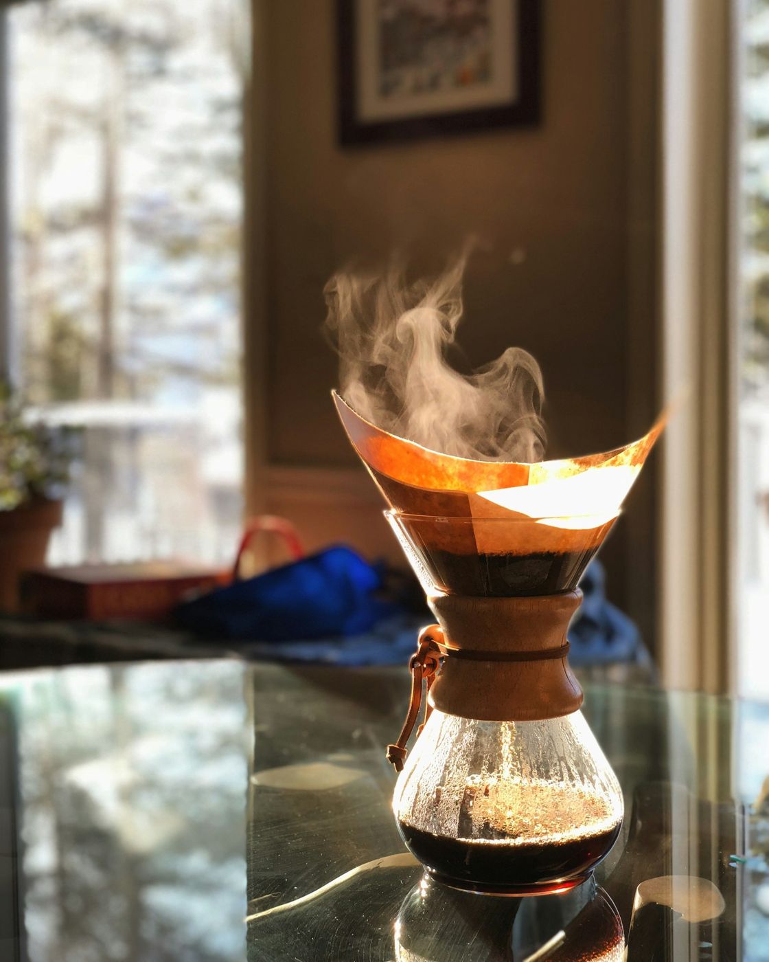 Steam rising off a pour-over brewer by a sunny window